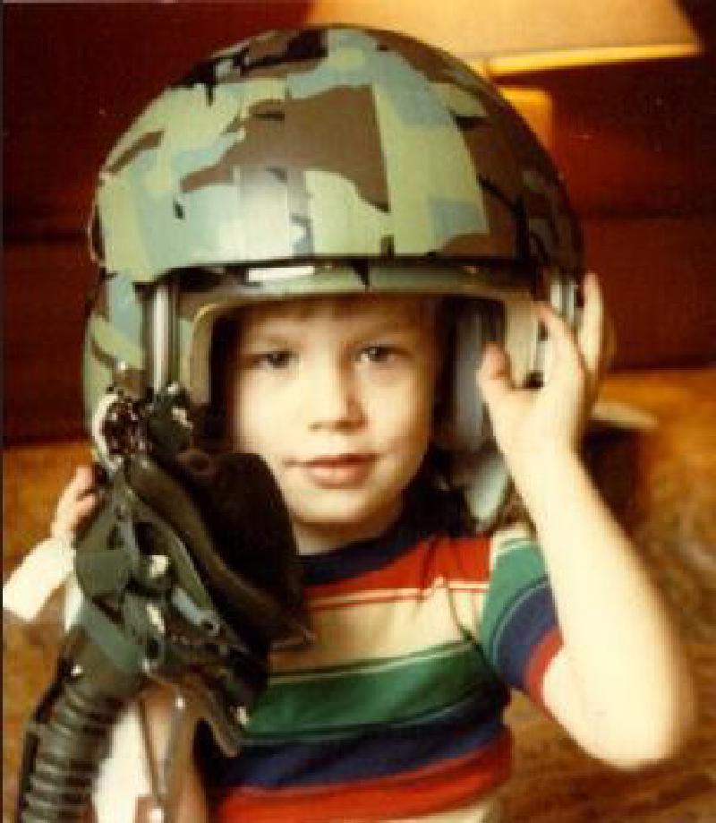 Young Brian Swiger wearing his father's combat helmet